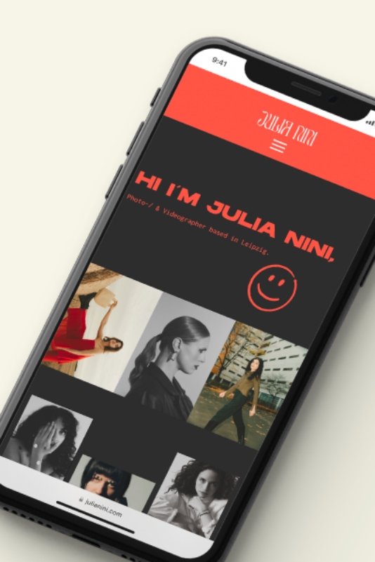 Alt-Text: "Professionelles Webdesign für 'Julia Nini', eine talentierte Fotografin und Videografin aus Leipzig, präsentiert auf einem Smartphone-Bildschirm. Die Website zeichnet sich durch ein klares, modernes Layout mit einer dynamischen Bildergalerie ihrer Arbeiten in Fotografie und Videografie aus. Der obere Bereich der Website hebt ihren Namen und das freundliche Begrüßungsmotto 'Hi I'm Julia Nini!' hervor, ergänzt durch ein lächelndes Emoji für eine persönliche Note.